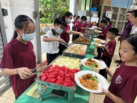Our P5 students taking turns to serve food to their peers during mealtimes